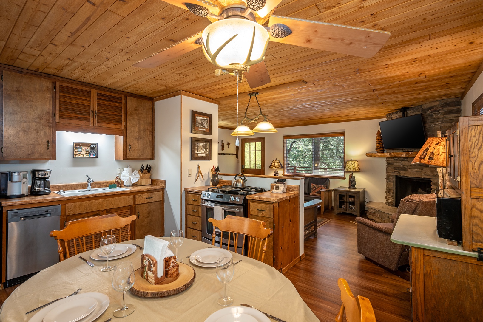 Step into your cozy cabin retreat with warm wood ceilings, a fully equipped kitchen, and a welcoming stone fireplace—your perfect home away from home awaits.