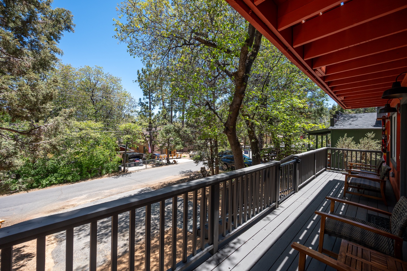 A spacious balcony overlooks a quiet, tree-lined street in a peaceful neighborhood. The sturdy deck and railings provide a perfect outdoor space to enjoy the natural surroundings.