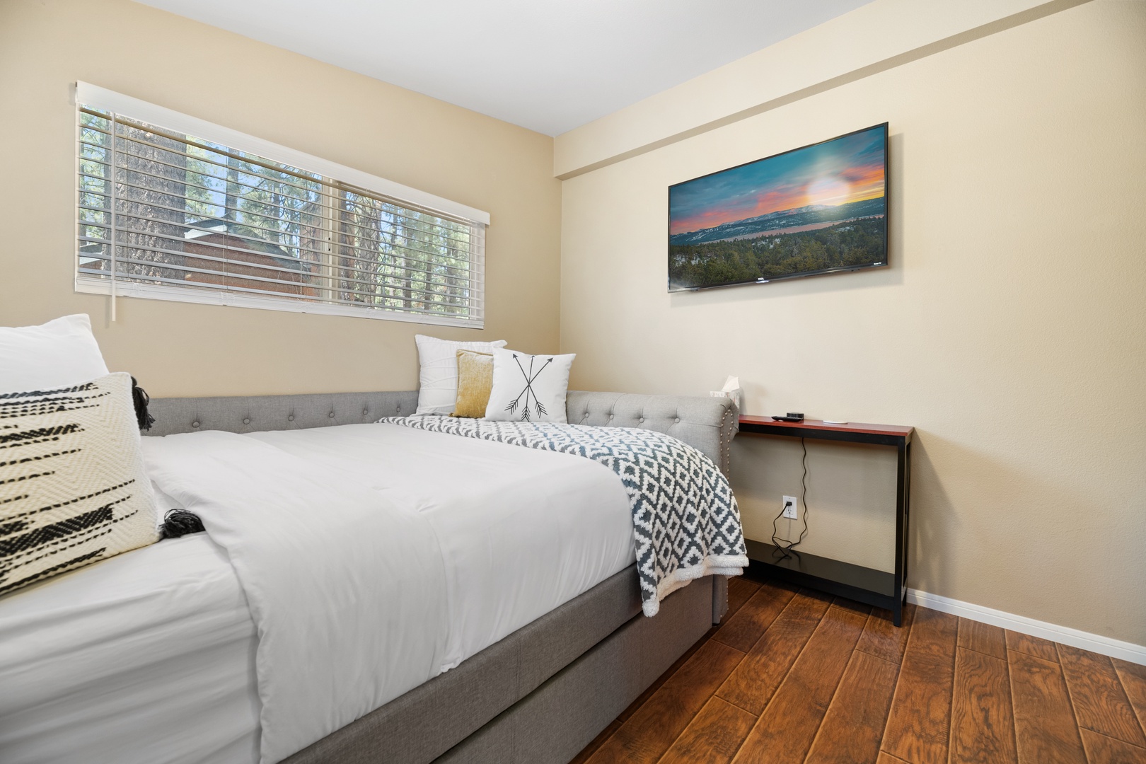 Sink into plush bedding and wake to natural light streaming through the blinds—your peaceful retreat awaits with warm tones, scenic wall art, and a cozy atmosphere.