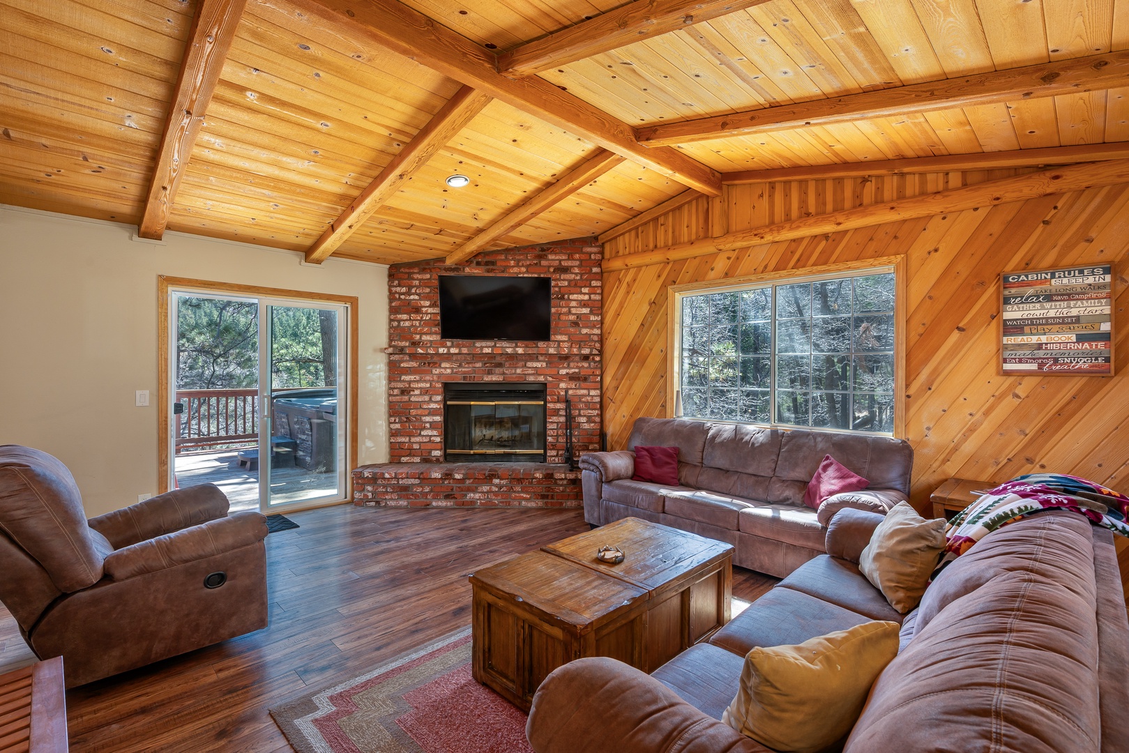 Cozy cabin living room with warm wood beams, brick fireplace, and plush seating where you'll unwind after mountain adventures.