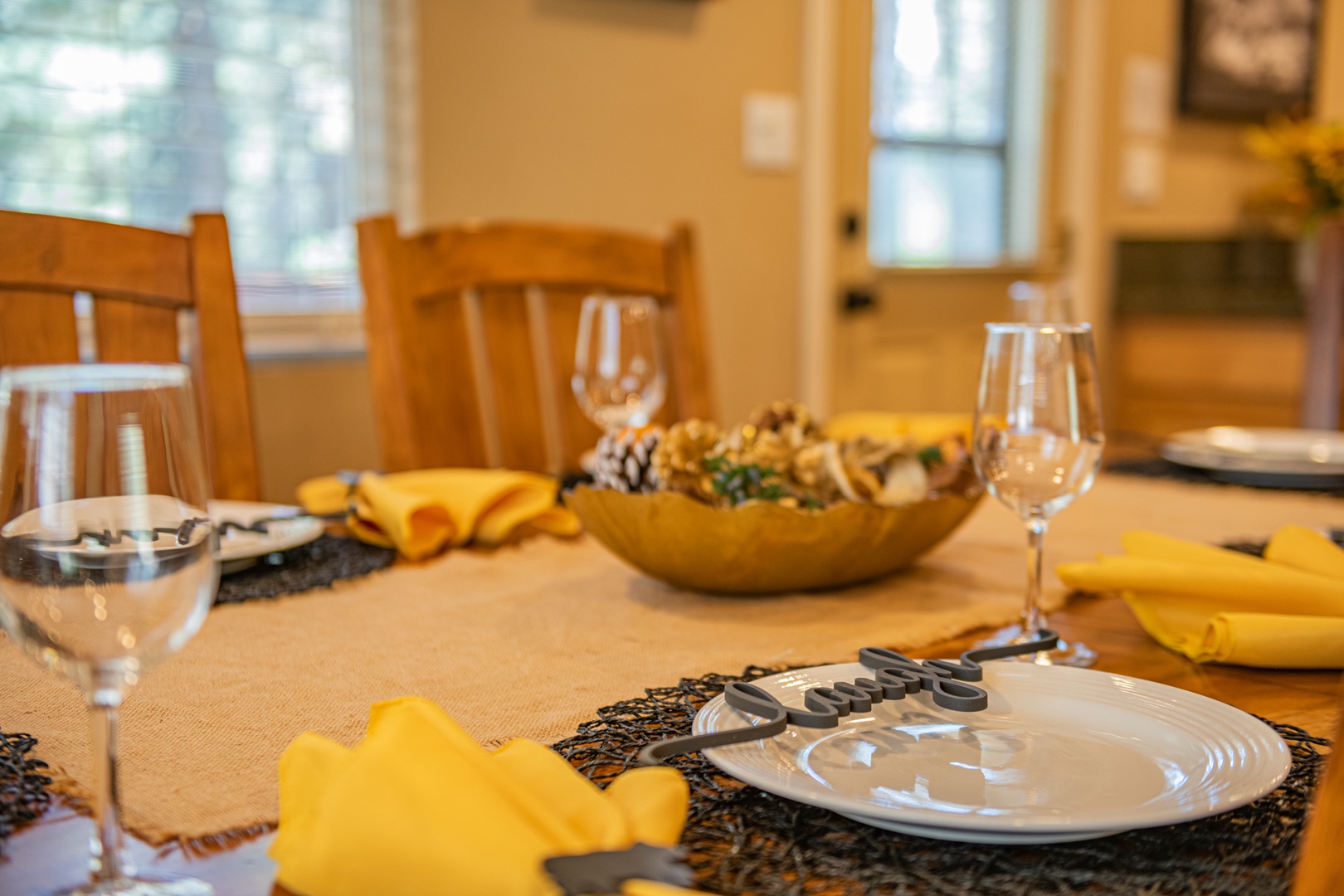 Your dining table awaits, beautifully set with sunny yellow napkins, elegant glassware, and a welcoming atmosphere that invites memorable meals together.