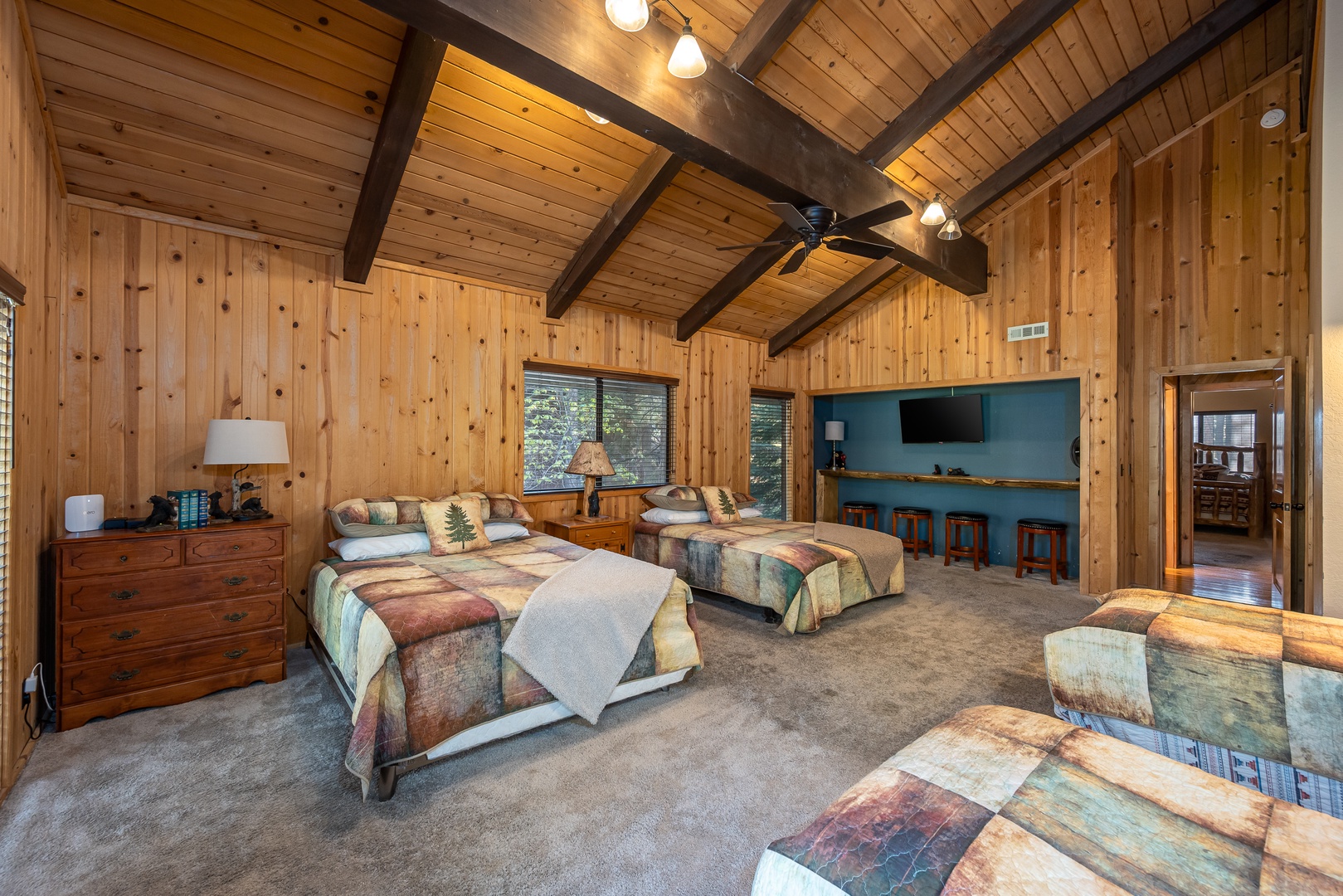Gather with your group in this inviting great room where rustic wood beams soar overhead and three cozy beds await. Unwind at the custom bar or settle in for movie night under soft lighting.