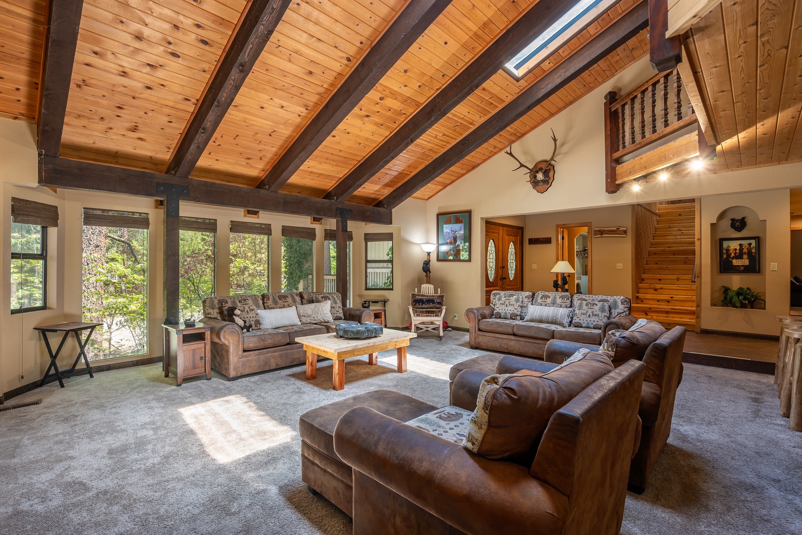 Sunlight pours through expansive windows into your spacious living area, where vaulted wood ceilings and rustic beams create a warm mountain retreat vibe. Sink into plush leather sofas and enjoy the open, airy charm of your home away from home.