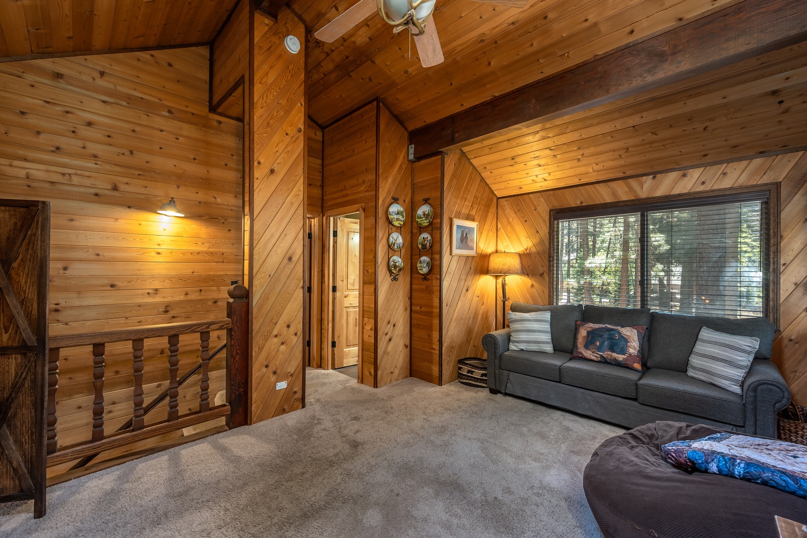 Unwind in your cozy loft retreat with vaulted wood ceilings, a comfy sofa, and serene forest views through large windows—your personal haven after a day of adventure.