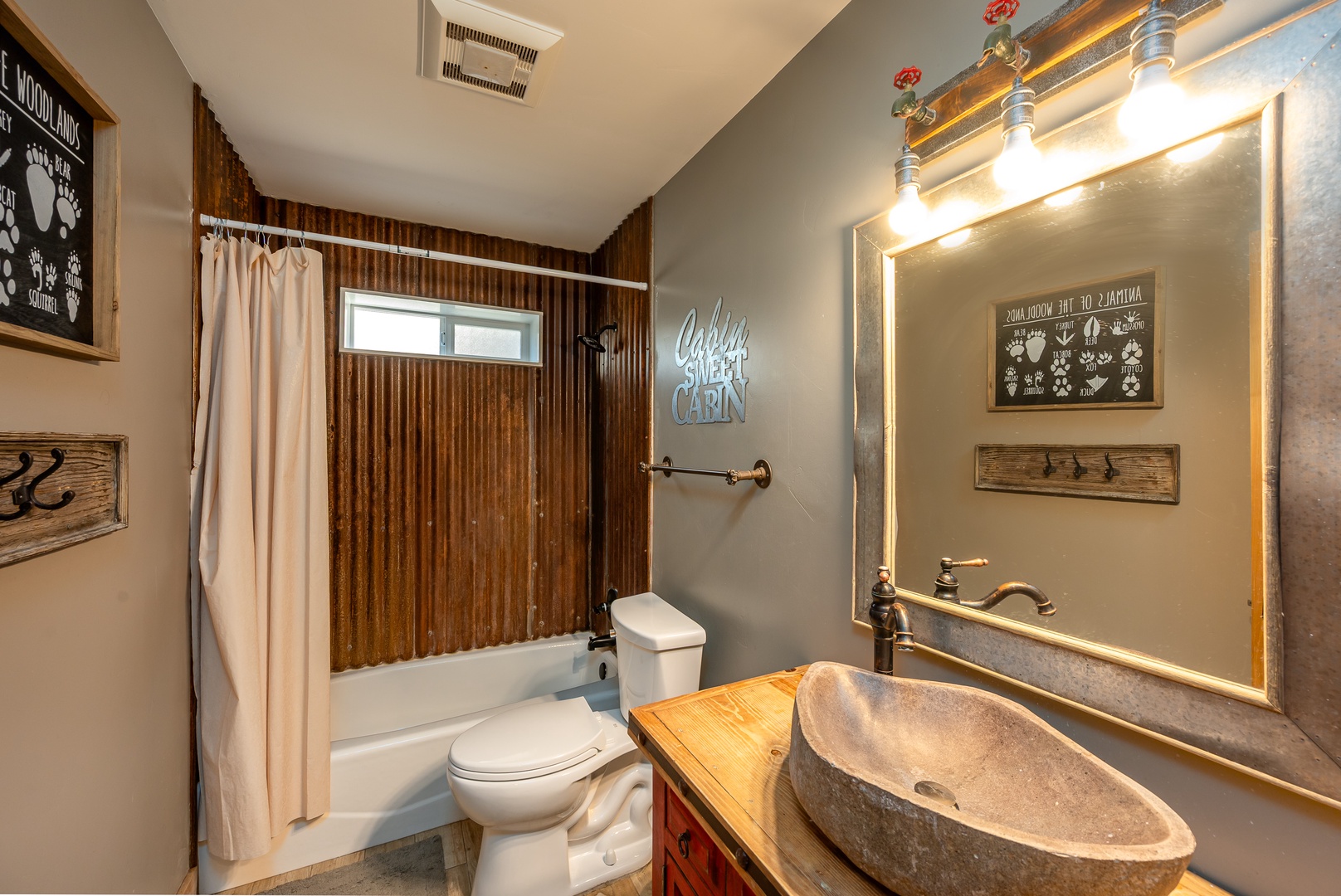 Step into your private retreat with rustic charm—warm wood tones, a unique stone vessel sink, and playful cabin-themed decor create a cozy, inviting space just for you.