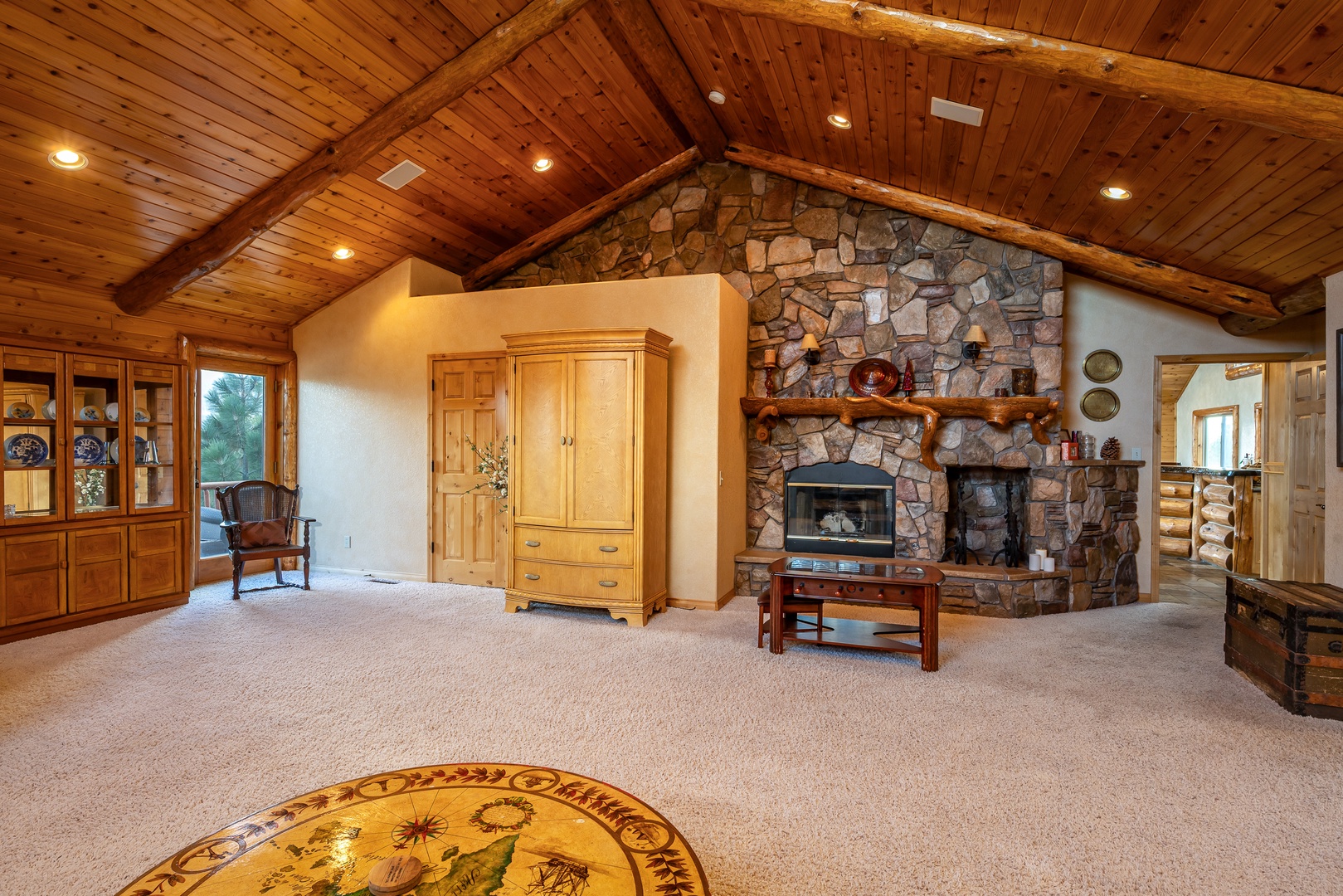 Gather around your stone fireplace in this spacious living area with soaring wood beam ceilings and rustic charm.