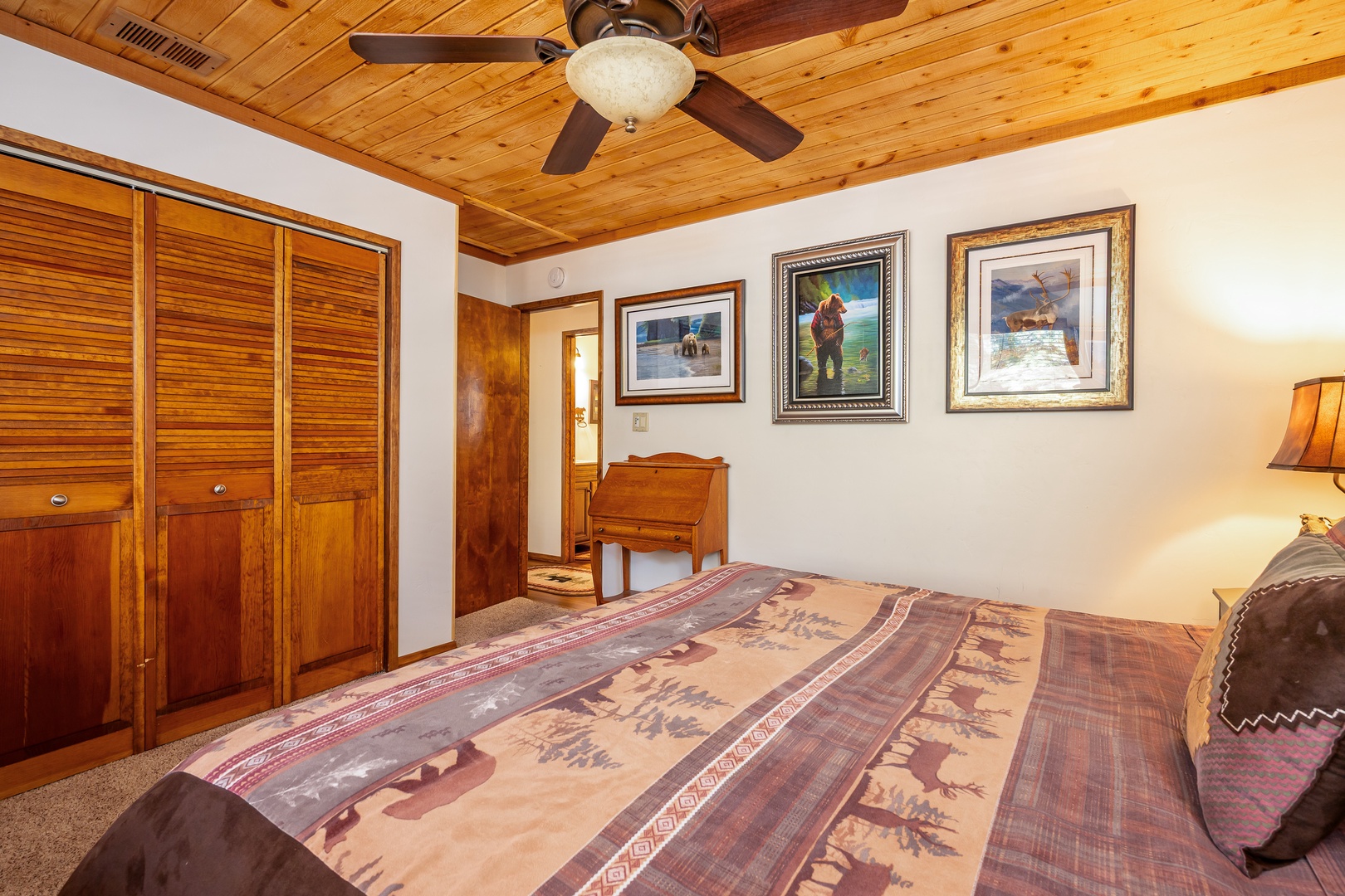 Unwind in your cozy bedroom featuring rich wood details, a ceiling fan to keep you comfortable, and charming fishing-themed artwork that adds a rustic touch to your mountain getaway.