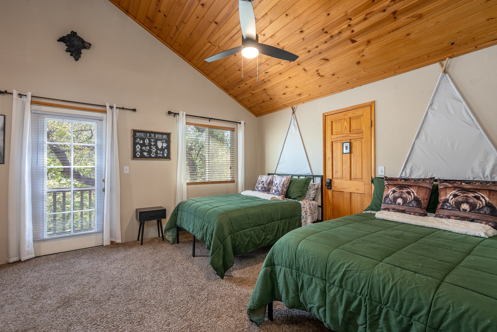Drift off under soaring wood ceilings and let natural light pour in through large windows that frame lush forest views. Two cozy beds await, one with charming tent canopy accents—perfect for families or groups seeking adventure and rest.