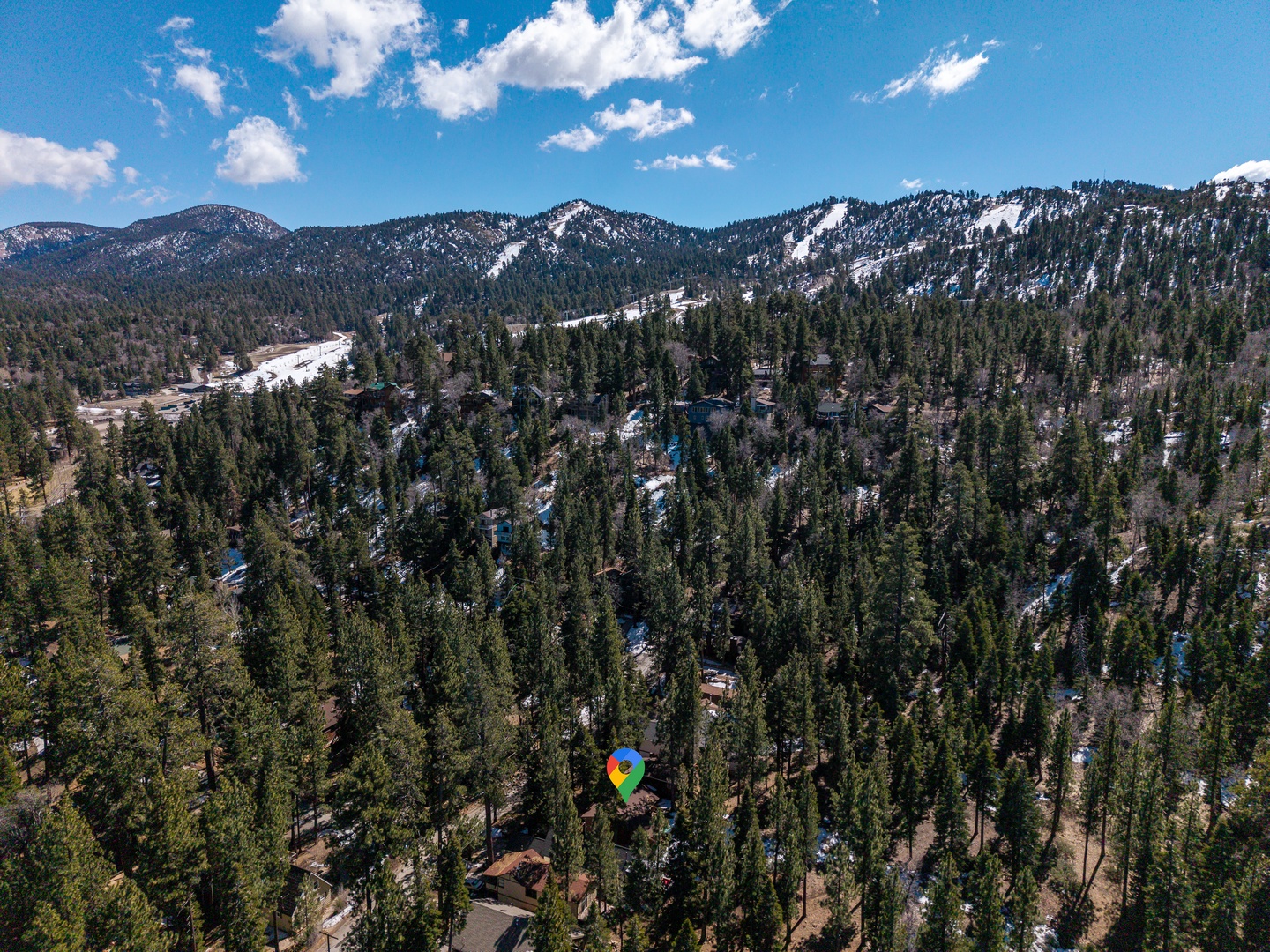 Aerial view showcasing the property's stunning mountain surroundings, nestled within a peaceful forested area with scenic peaks visible in the distance.
