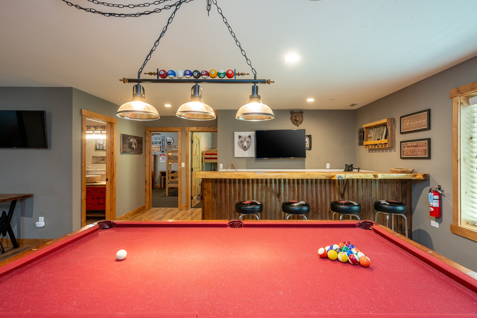 Your game room awaits with a vibrant red billiard table, rustic bar seating, and playful décor—perfect for friendly competition and making memories with loved ones.