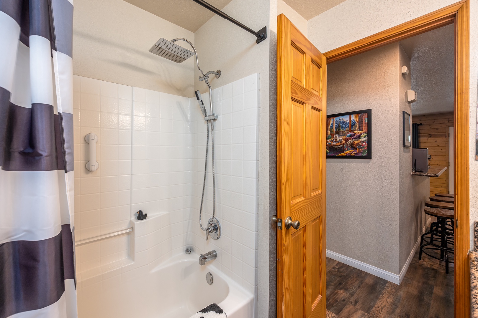 Your private bathroom features a clean white tub and shower combo with rainfall showerhead. Fresh towels and a functional design make it easy to unwind after exploring the area.
