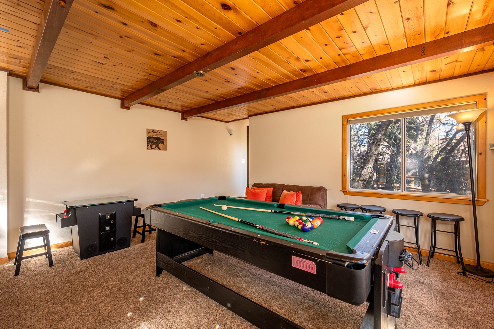 Your own private game room awaits—challenge friends to billiards or unwind beneath gorgeous wood-beamed ceilings with peaceful forest views through the window.