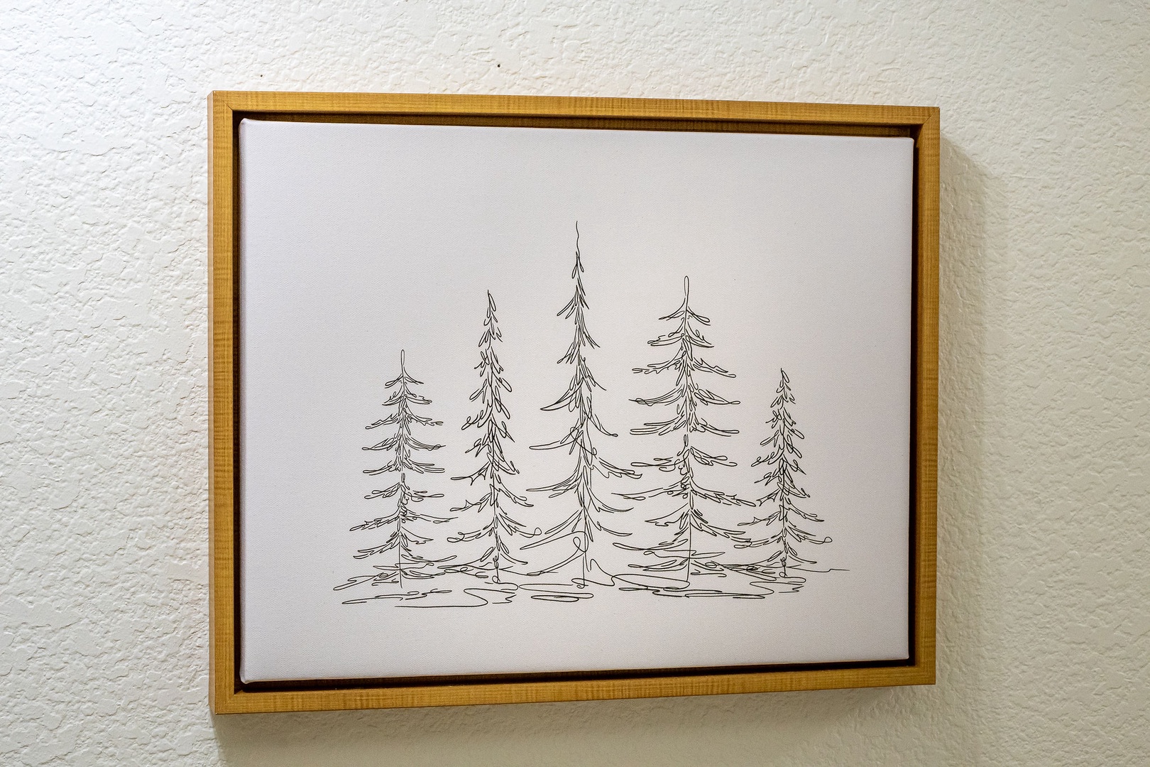 Charming hand-drawn pine tree artwork in a natural wood frame adds a cozy, rustic touch to your wall space.
