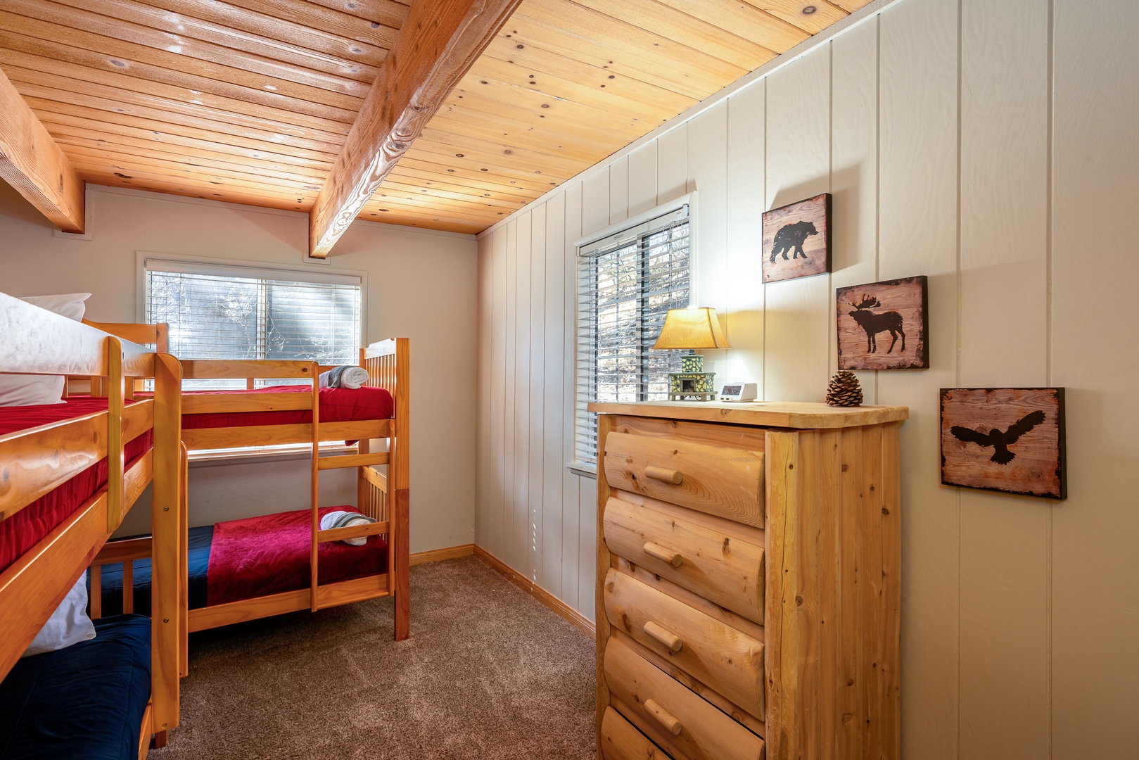 Cozy mountain-themed bedroom with rustic wooden bunk beds and charming wildlife artwork creates the perfect retreat for kids or groups.