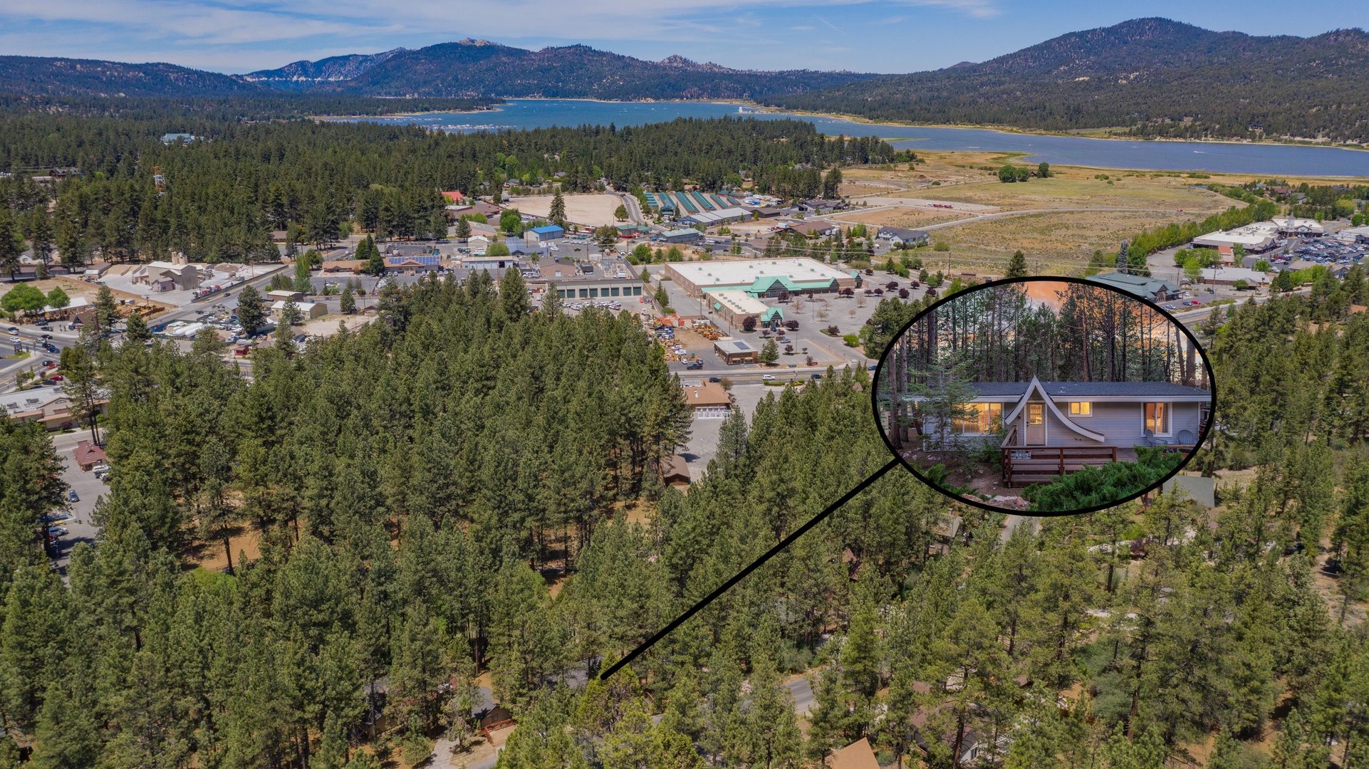 Aerial view of a mountain lakeside community, with the property nestled in a peaceful forest setting near town amenities and stunning natural surroundings.