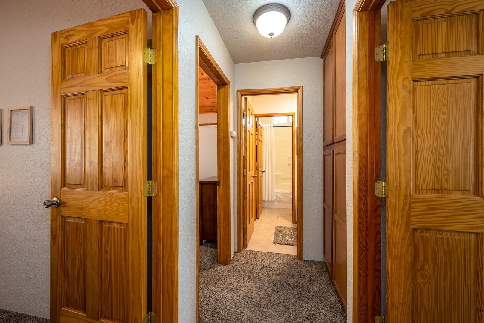 A welcoming hallway connects your private spaces with warm wood doors, soft carpet underfoot, and bright lighting that guides you through your mountain retreat.