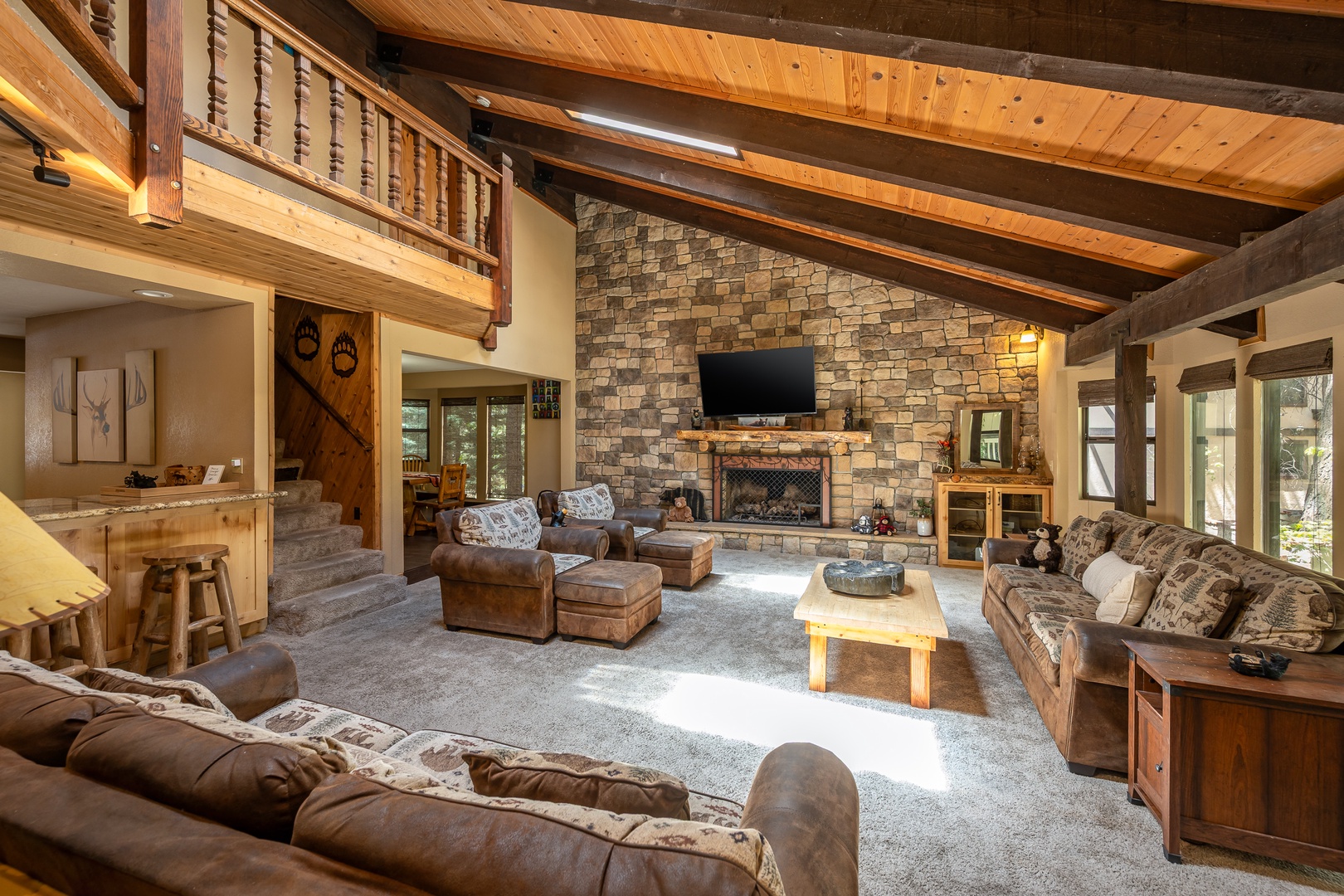 Unwind in this spacious living room with soaring wood-beam ceilings, plush leather seating, and a stunning stone fireplace that invites cozy evenings by the fire.