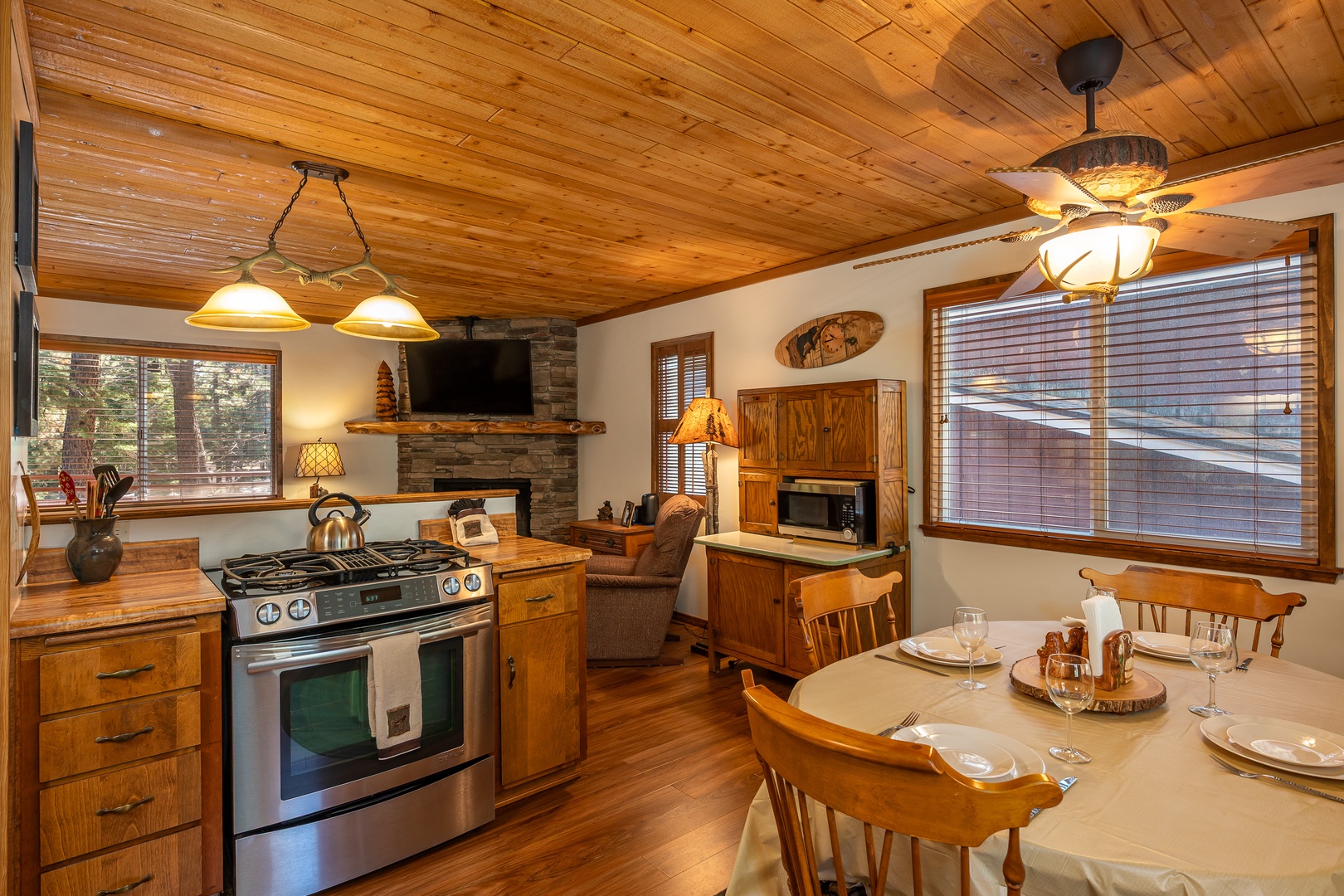 Cozy up in your rustic cabin retreat where wood-paneled ceilings and a stone fireplace create warmth, while a fully equipped kitchen invites you to prepare meals surrounded by charming, mountain-inspired touches.