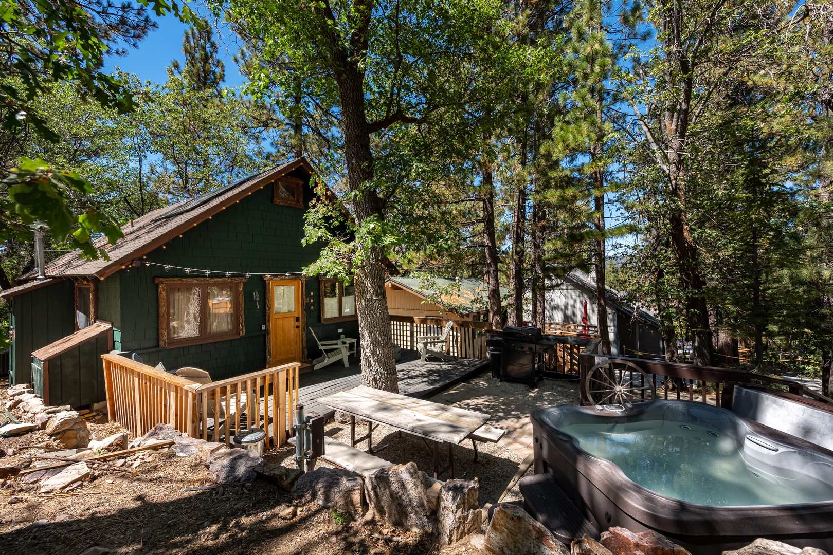 A cozy forest cabin nestled among towering pines and oaks, featuring an inviting hot tub on a spacious wooden deck where you can soak under the trees and stars.