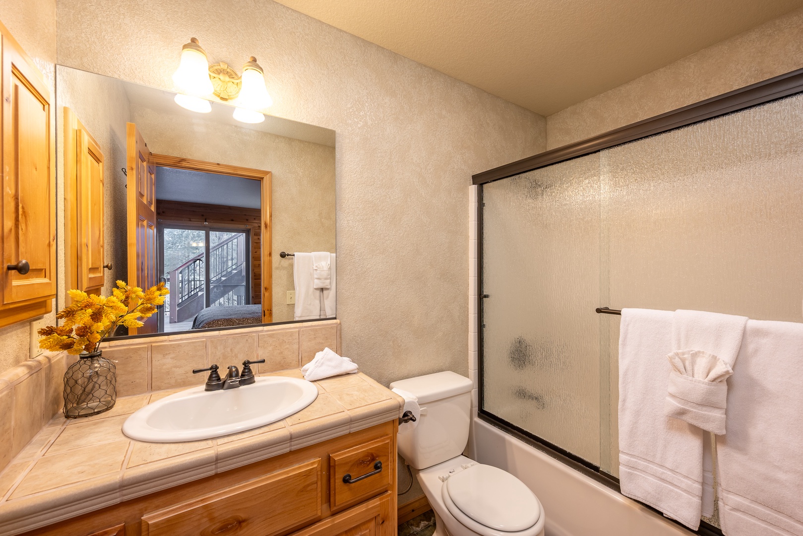 Step into your private bathroom featuring warm wood vanity, fresh towels, and a spacious shower for your comfort.