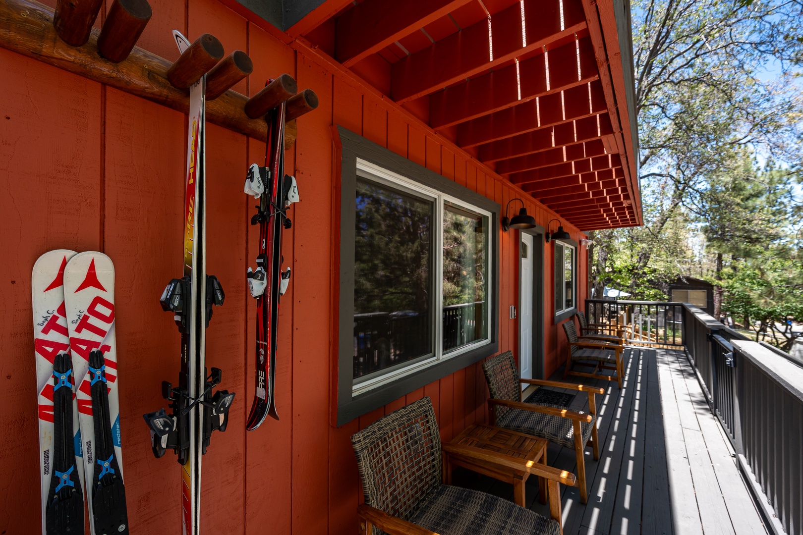A bright orange deck with ski storage, comfortable wicker seating, and forest views—perfect for après-ski relaxation and storing your gear right outside the door.