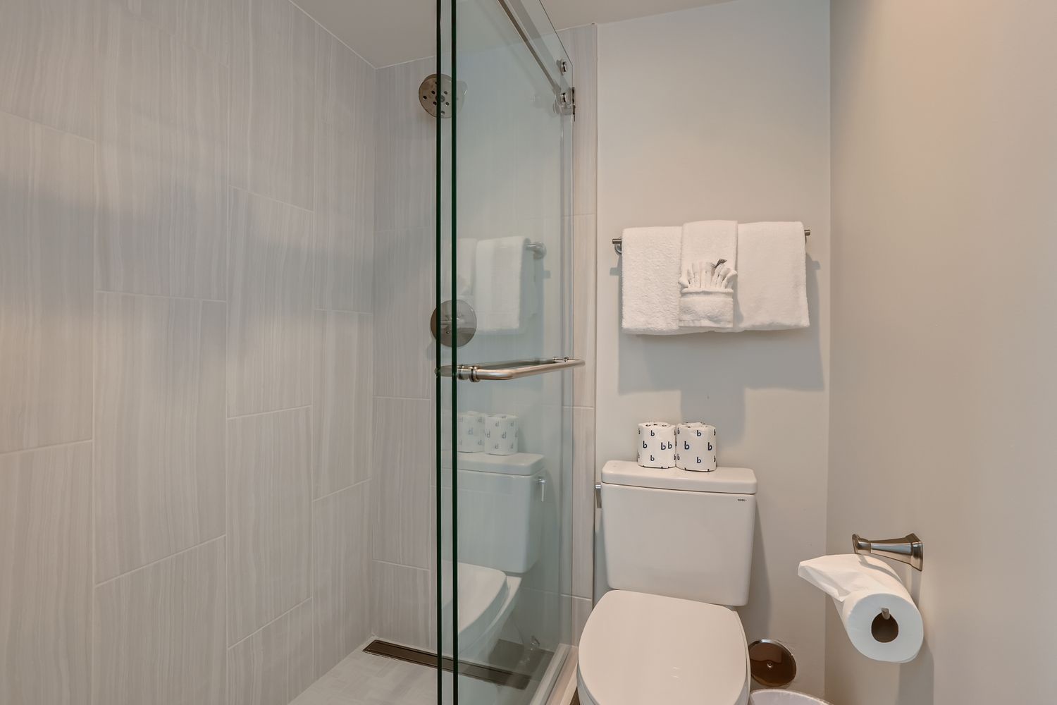 Step into your pristine ensuite with modern glass shower, plush towels, and thoughtful amenities ready for your refreshing morning routine.