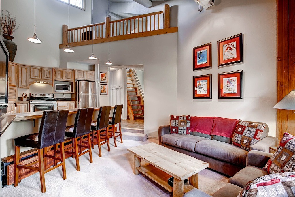 Relax in your spacious loft with soaring ceilings, where the open-plan living flows from kitchen to cozy seating area beneath a charming wooden loft.