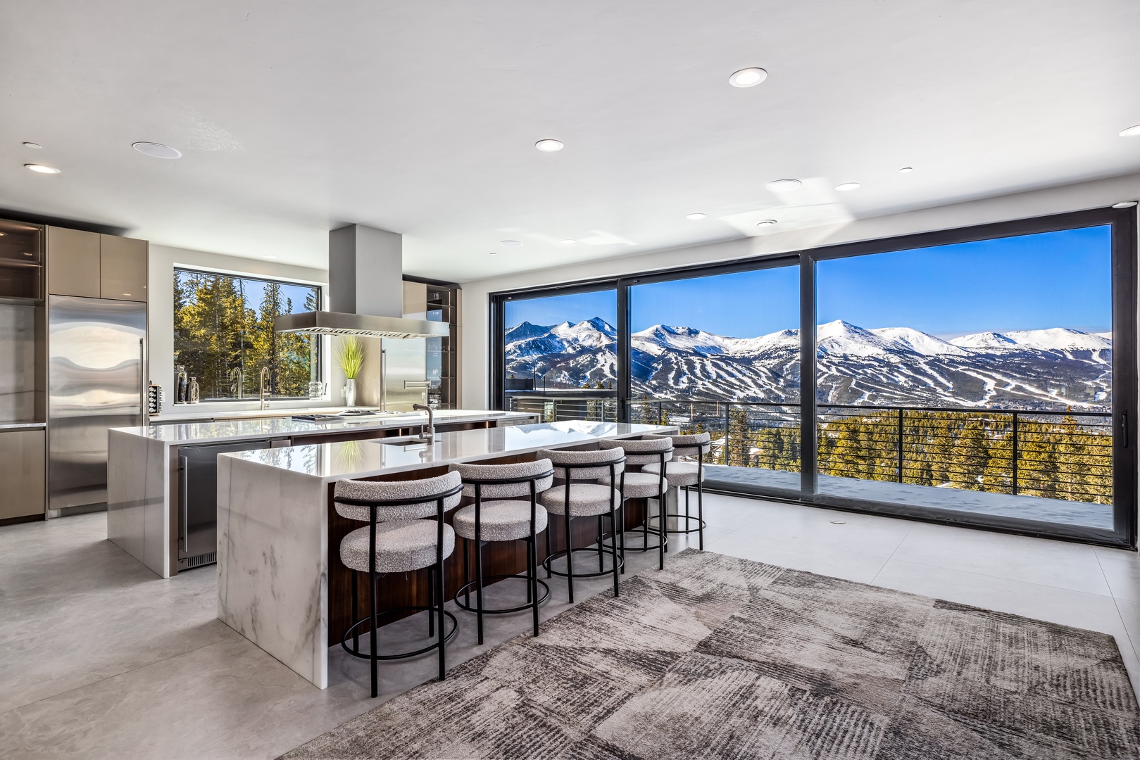 Cook with stunning mountain views as your backdrop in this modern kitchen featuring a spacious island and panoramic windows.