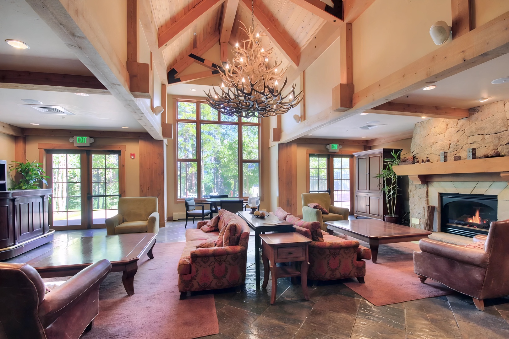 Unwind by the crackling fireplace in this stunning communal lounge, where soaring timber beams and cozy seating create your perfect mountain retreat atmosphere.
