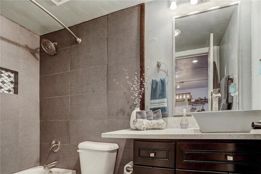 Step into your elegant bathroom featuring sleek gray tile, modern fixtures, and thoughtful touches that make your stay feel luxurious.