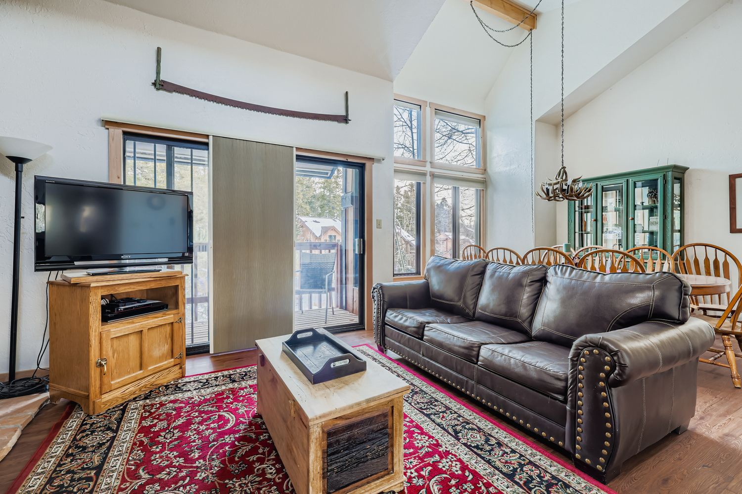 Relax in your spacious living room featuring a plush leather sofa, rustic charm, and mountain views through expansive windows.