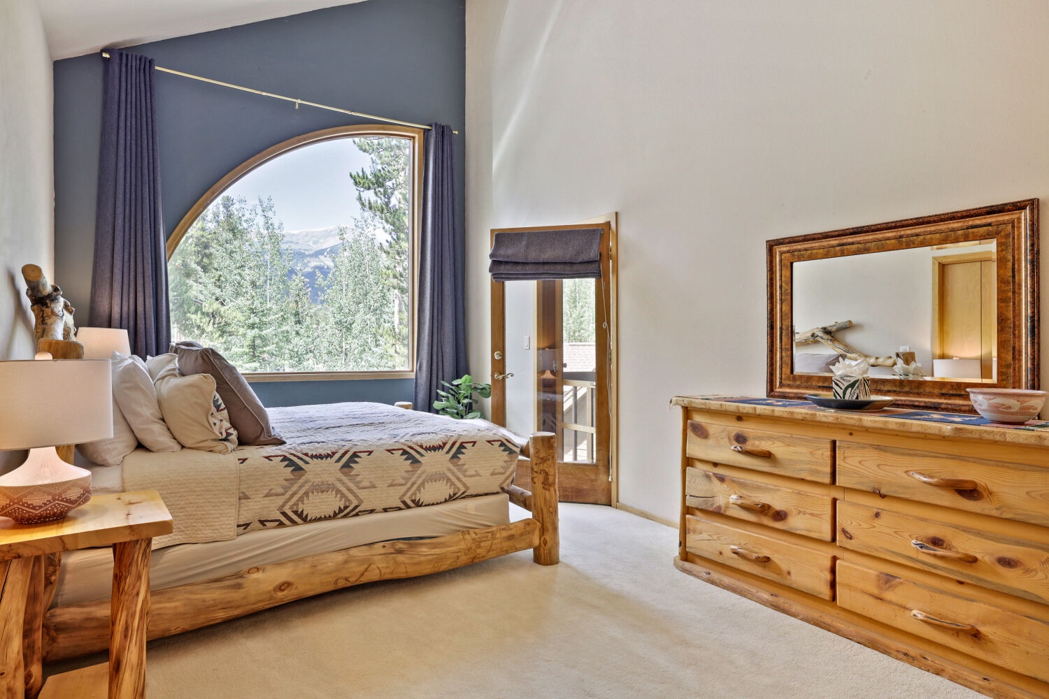 Wake up to breathtaking mountain vistas framed by a stunning arched window, where rustic charm meets modern comfort in your own peaceful retreat.
