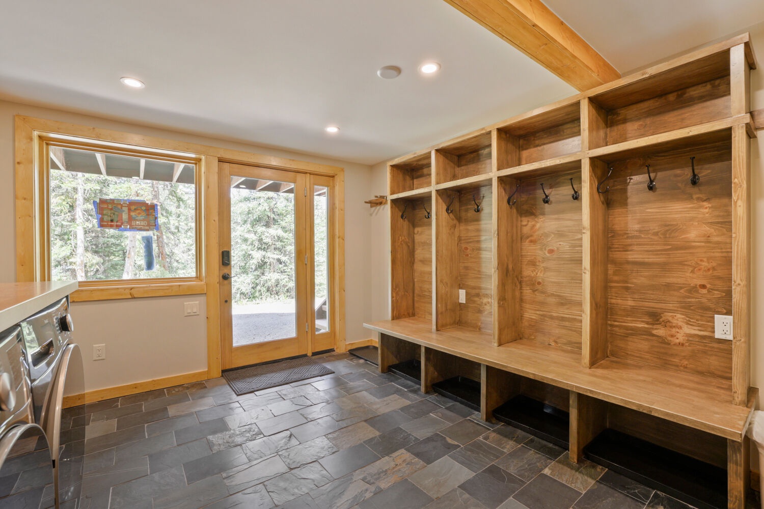 Step into your private mudroom with custom wood cubbies and bench seating—perfect for organizing gear after a day exploring the outdoors. The space flows seamlessly to the natural surroundings just beyond the door.