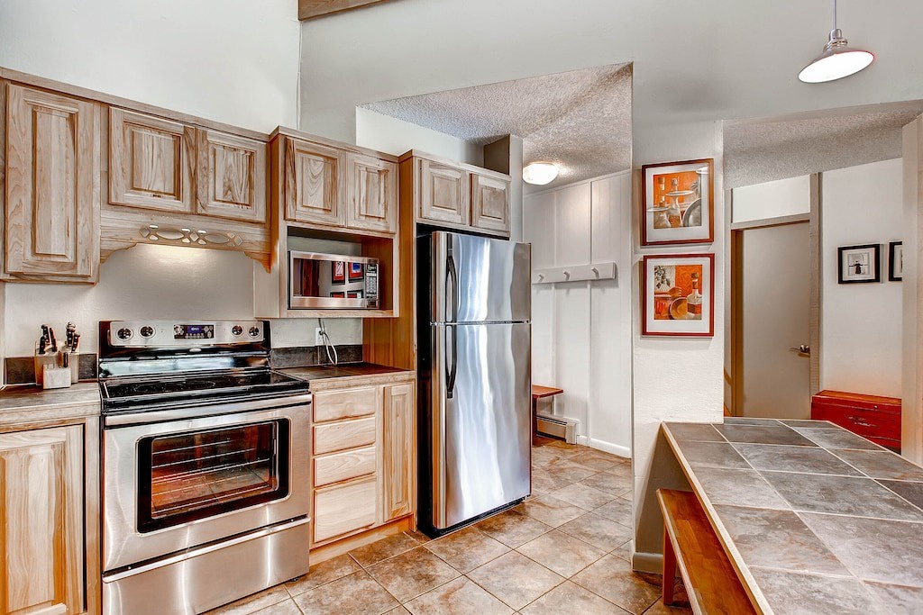 Your fully equipped kitchen features warm wood cabinets, stainless steel appliances, and tile countertops—perfect for preparing memorable meals during your stay.