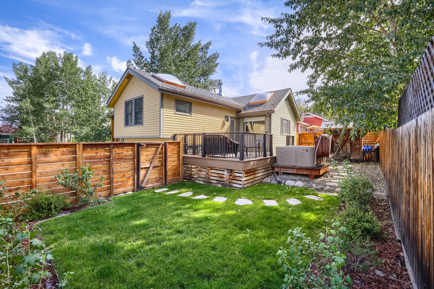 The charming backyard features a private deck and grassy lawn, perfect for relaxing under sunny skies and enjoying your outdoor retreat.