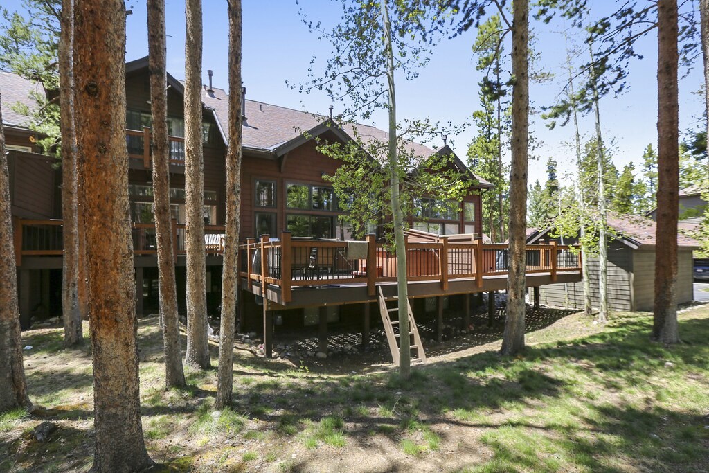 Multi-level mountain retreat nestled among tall pines with expansive wooden deck perfect for outdoor relaxation and forest views.