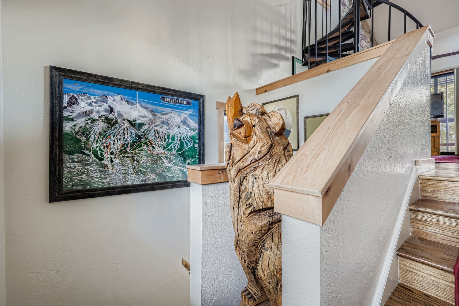 A stunning bear carving greets you at the wooden staircase, with mountain ski maps creating an alpine atmosphere in this charming multi-level space.