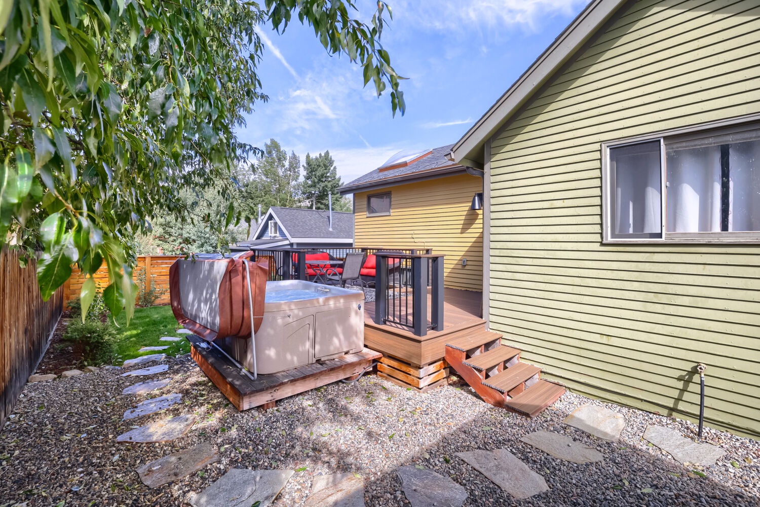 The property features a private backyard deck and hot tub nestled among mature trees, offering a peaceful outdoor retreat after a day of exploring the area.