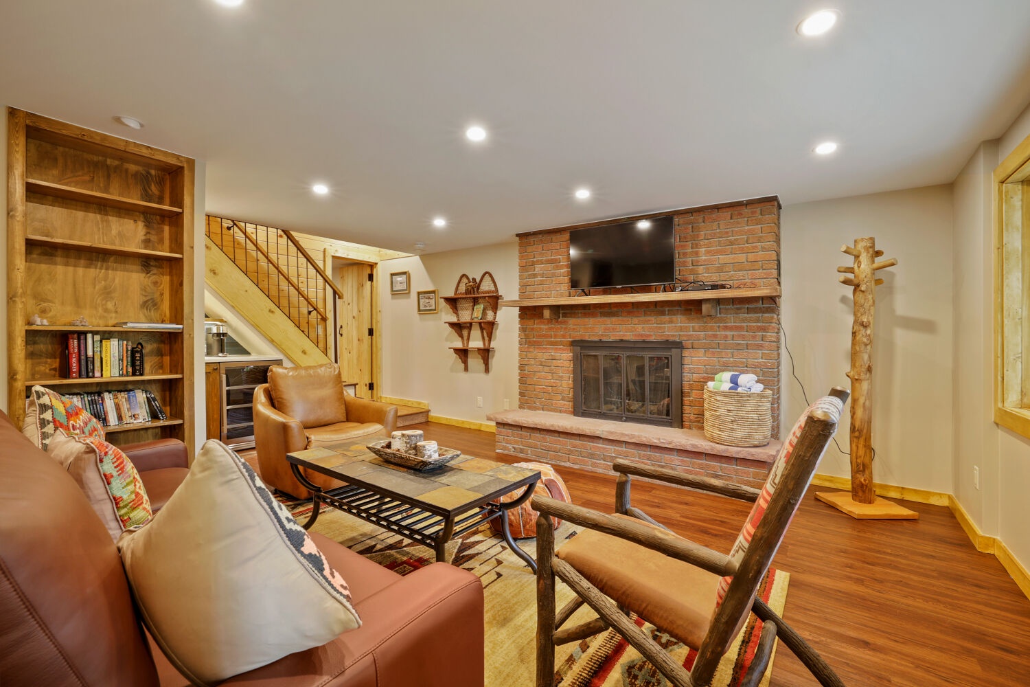Curl up with a book by the brick fireplace in this cozy living room, where warm wood tones and comfortable seating create your perfect retreat after a day of mountain adventures.