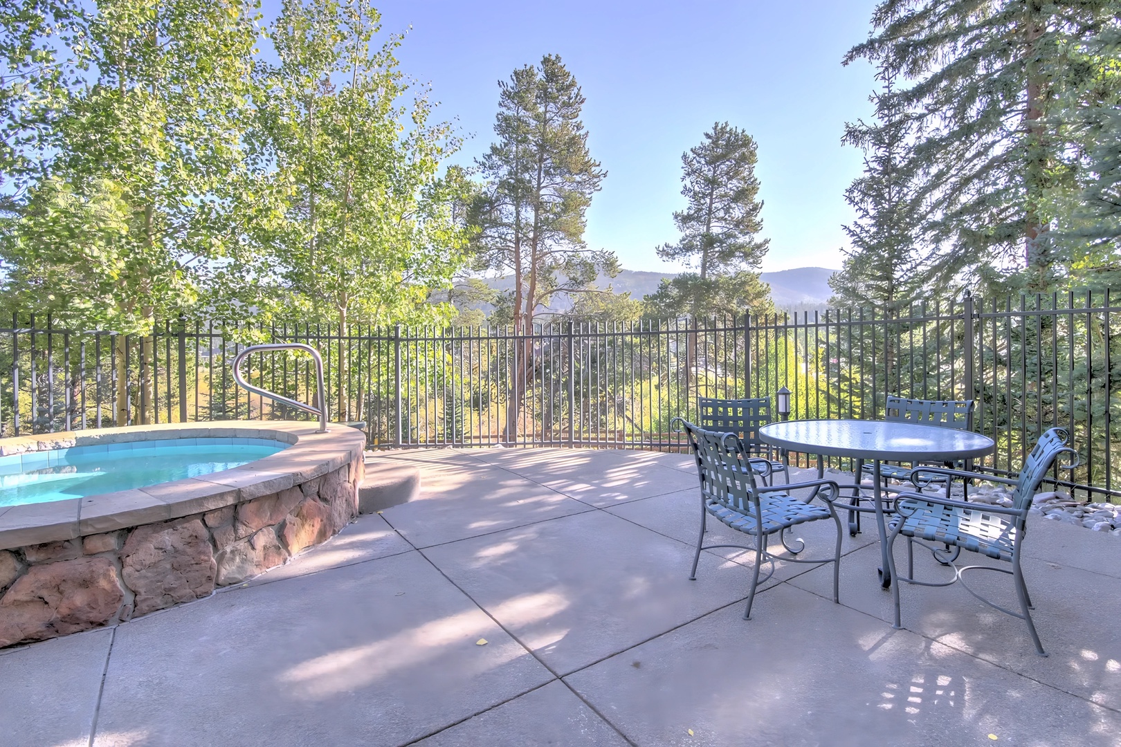 Unwind on your private patio with hot tub and dining area, surrounded by towering trees and mountain views.