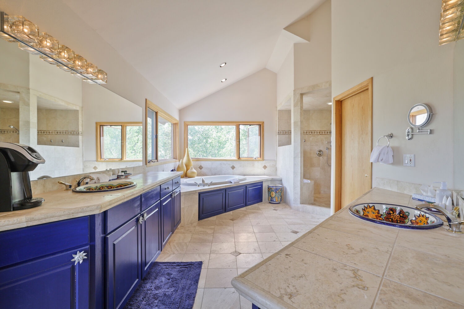 Indulge in your private spa-like bathroom with a luxurious soaking tub, dual vanities, and abundant natural light streaming through the windows. Your retreat includes a walk-in shower and ample counter space for a relaxing getaway.