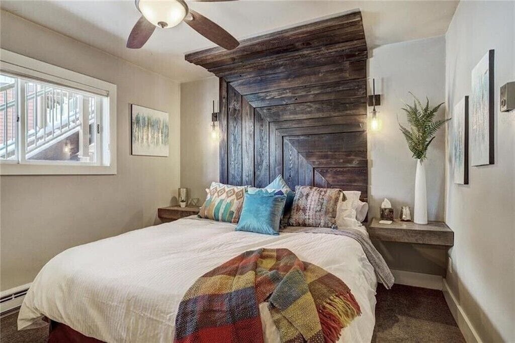 Drift off in your cozy bedroom featuring rustic wood headboard, colorful textiles, and warm lighting for perfect rest.