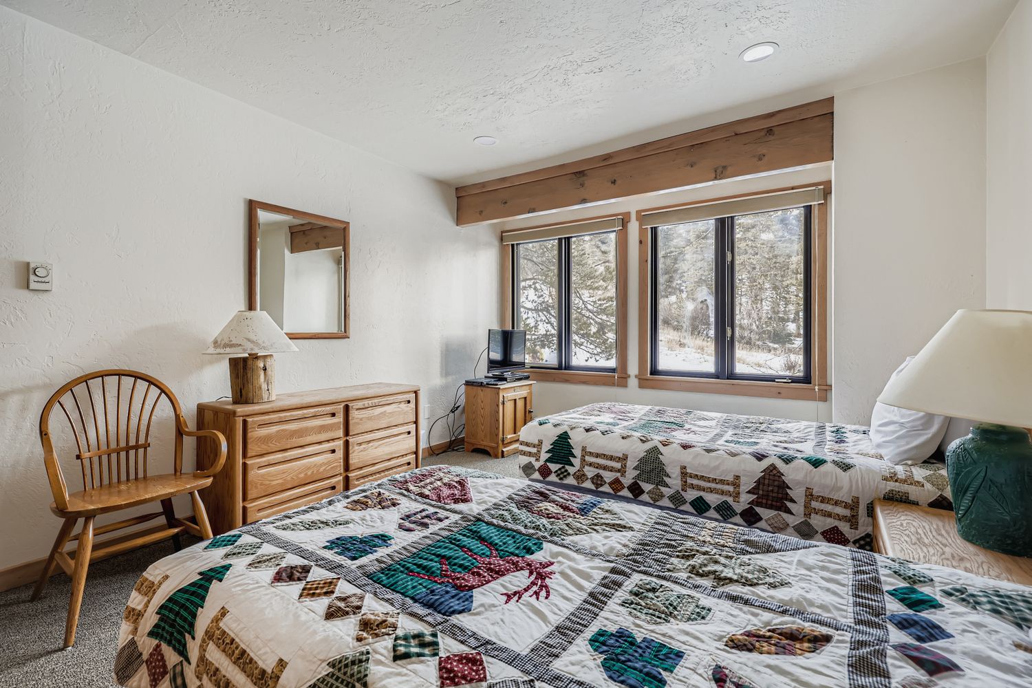 Cozy up in this charming bedroom where handmade quilts and rustic wood beams create the perfect mountain retreat atmosphere for your peaceful getaway.