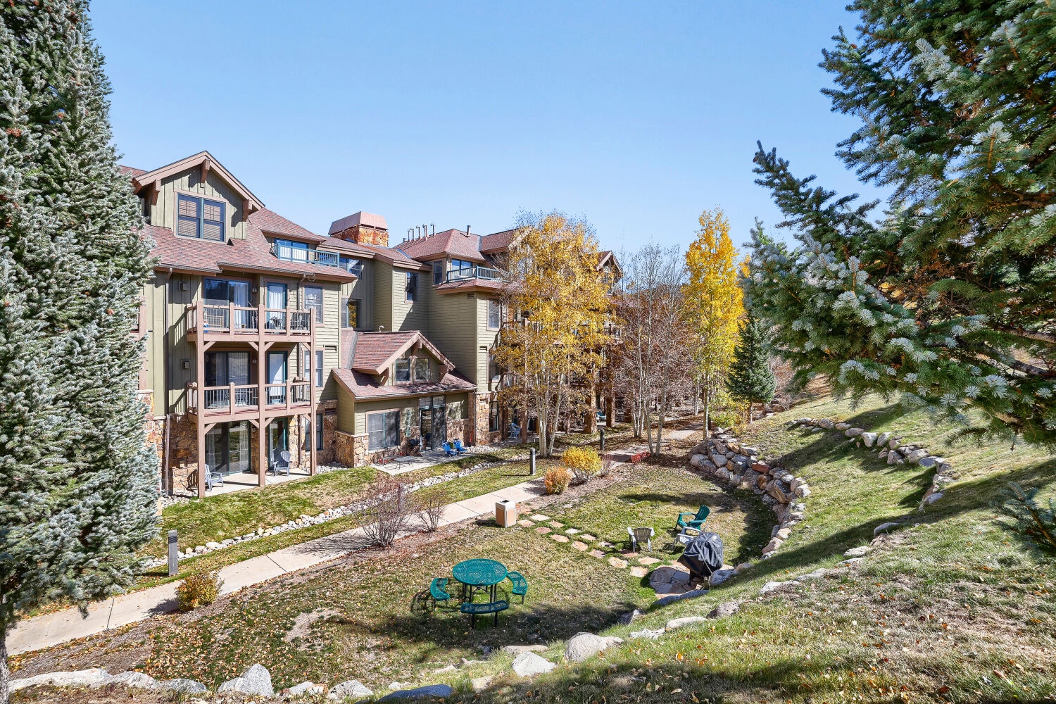 The property features a spacious landscaped courtyard with evergreens and aspens, natural stone pathways, and a peaceful fire pit area—perfect for gathering under open skies.