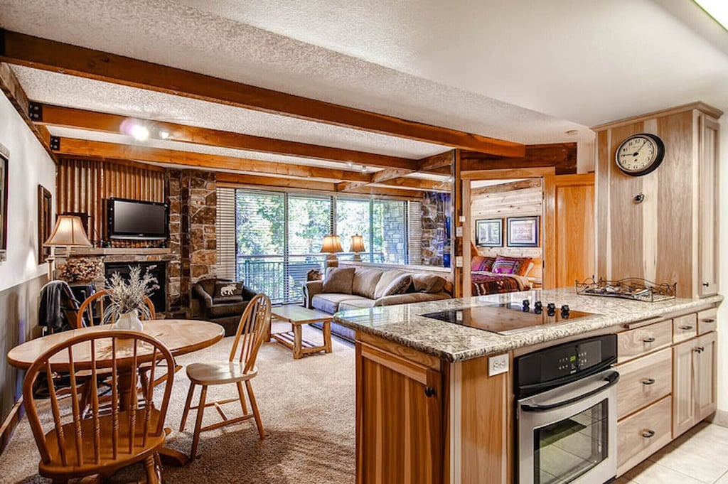 Relax in this warm open-concept space where rustic beams frame your mountain retreat, complete with stone fireplace and fully equipped kitchen.