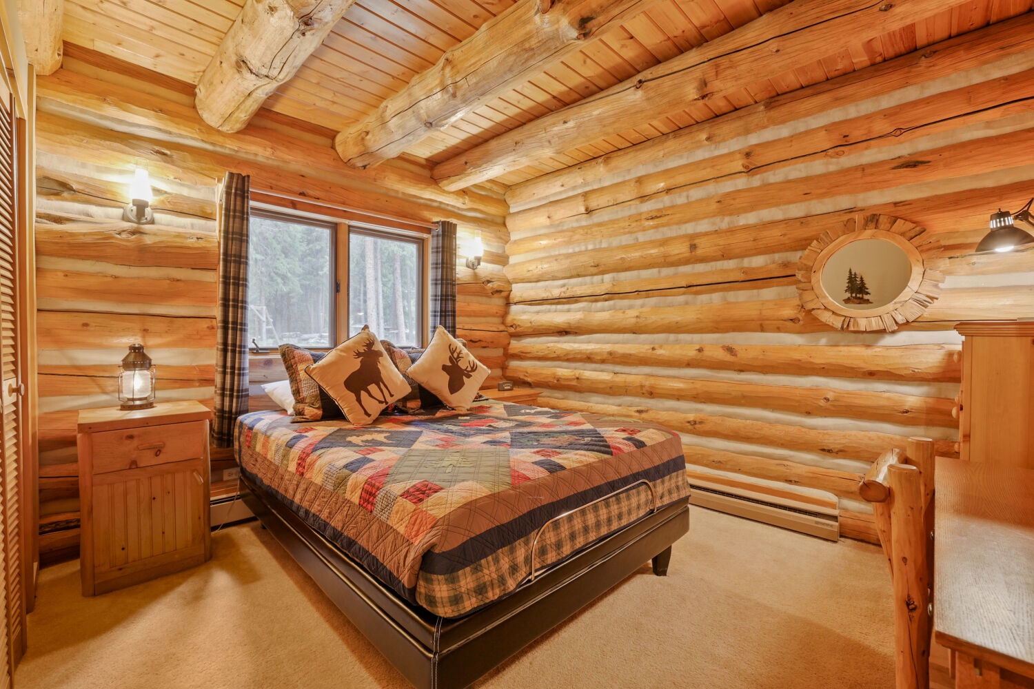 Drift off beneath exposed log beams in this cozy bedroom, where warm wood wraps around you and plaid accents bring rustic charm. Your woodland-themed bed overlooks peaceful forest views through the window.