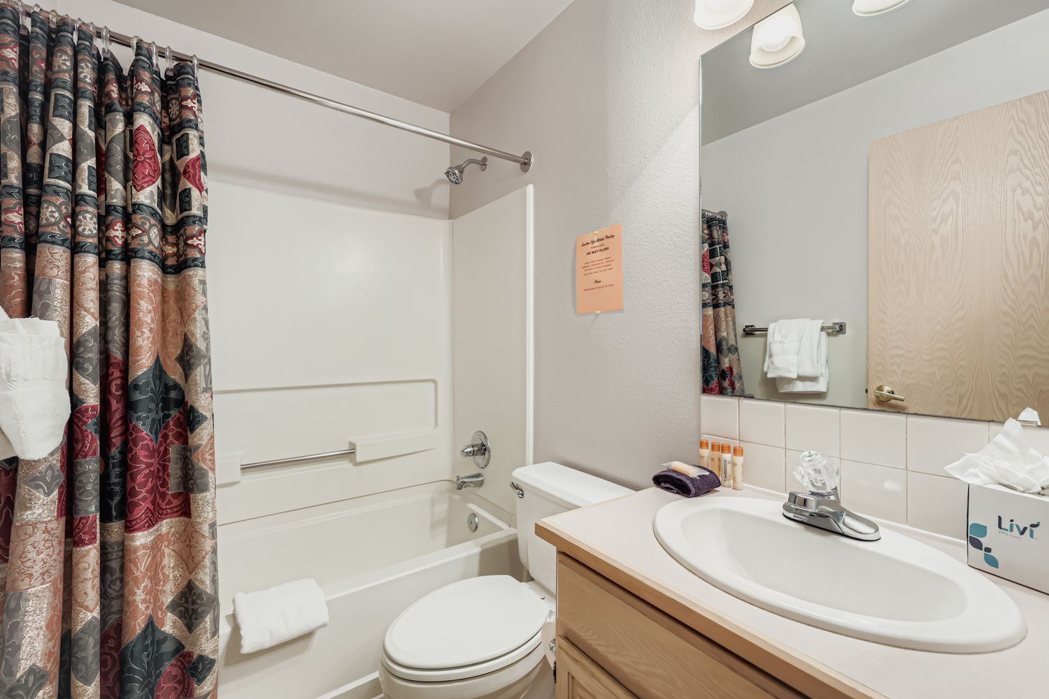 Your private bathroom features a relaxing tub-shower combo with tropical-patterned curtains and fresh towels waiting for you.