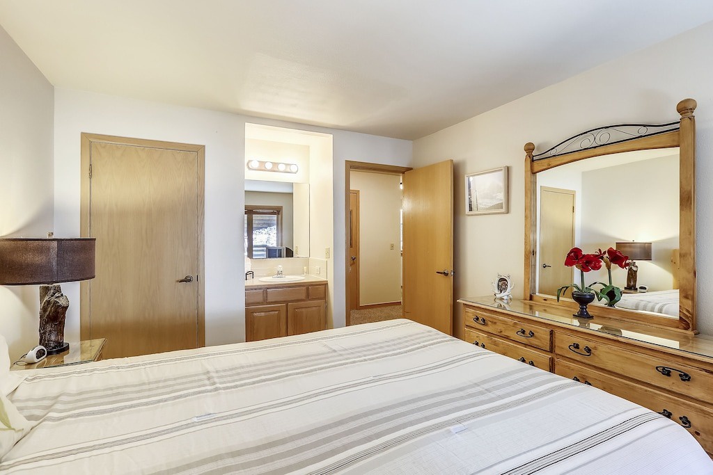 Relax in your cozy bedroom featuring a comfortable bed, rustic wooden dresser, and convenient ensuite access for your mountain getaway.