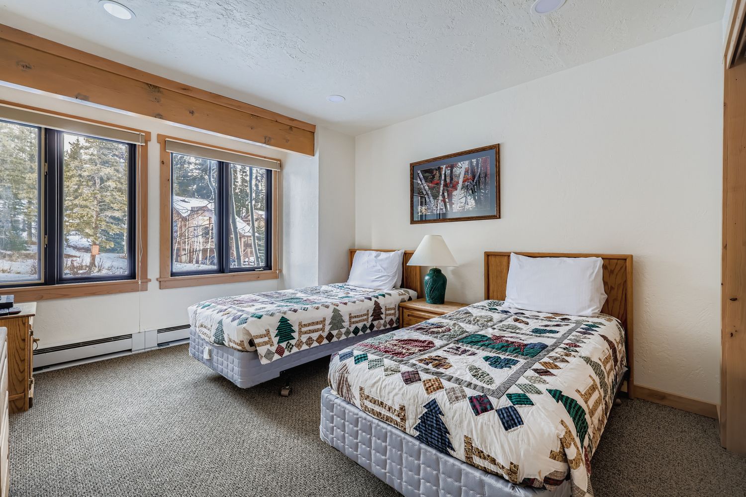 Rest peacefully in your cozy twin bedroom with handcrafted quilts and forest views through charming wood-framed windows.