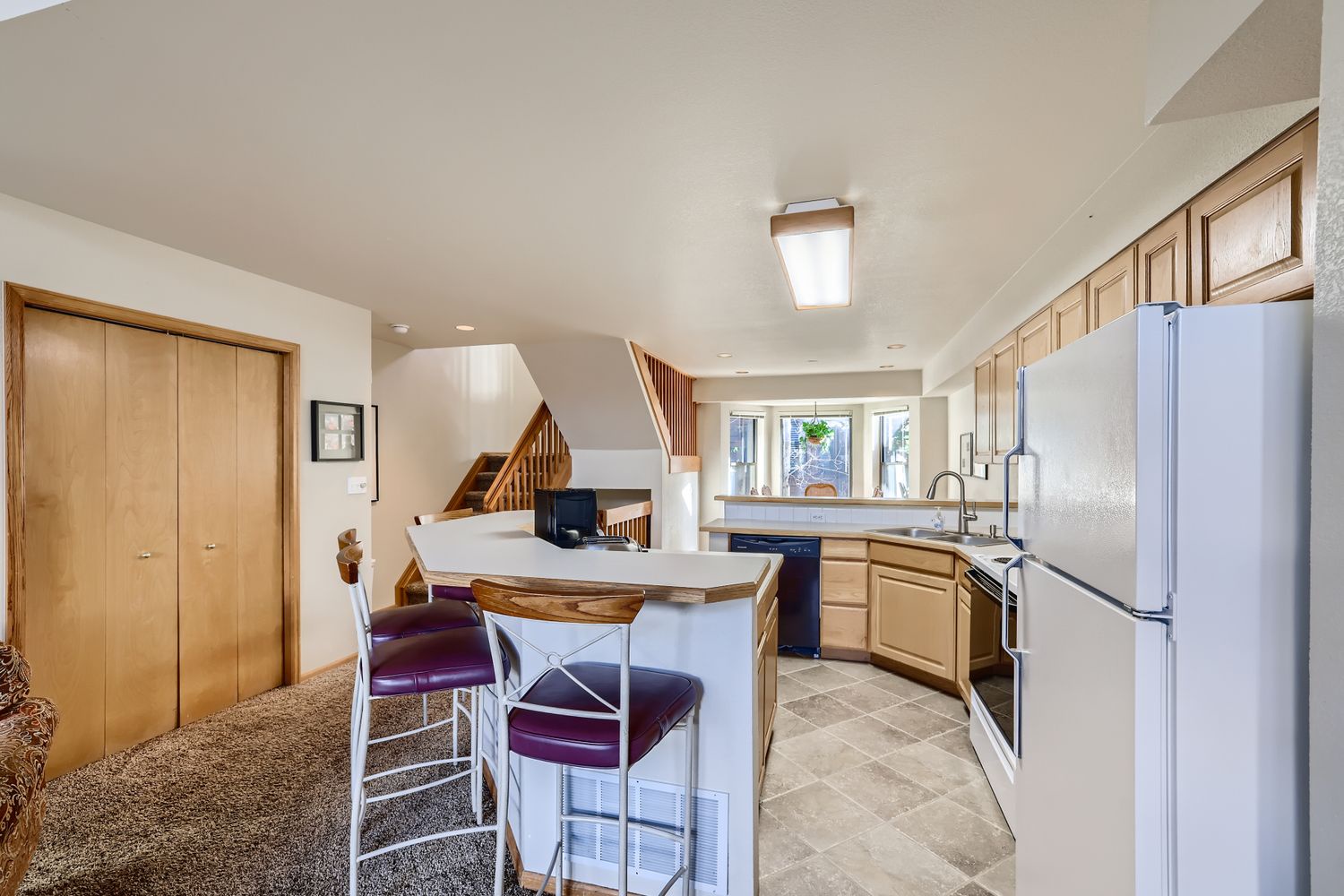 Your spacious kitchen invites culinary adventures with warm wood cabinetry, modern appliances, and a welcoming breakfast bar perfect for morning coffee.